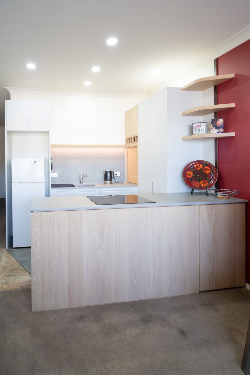 Kitchen with an oak peninsula, floating shelves and a red feature wall